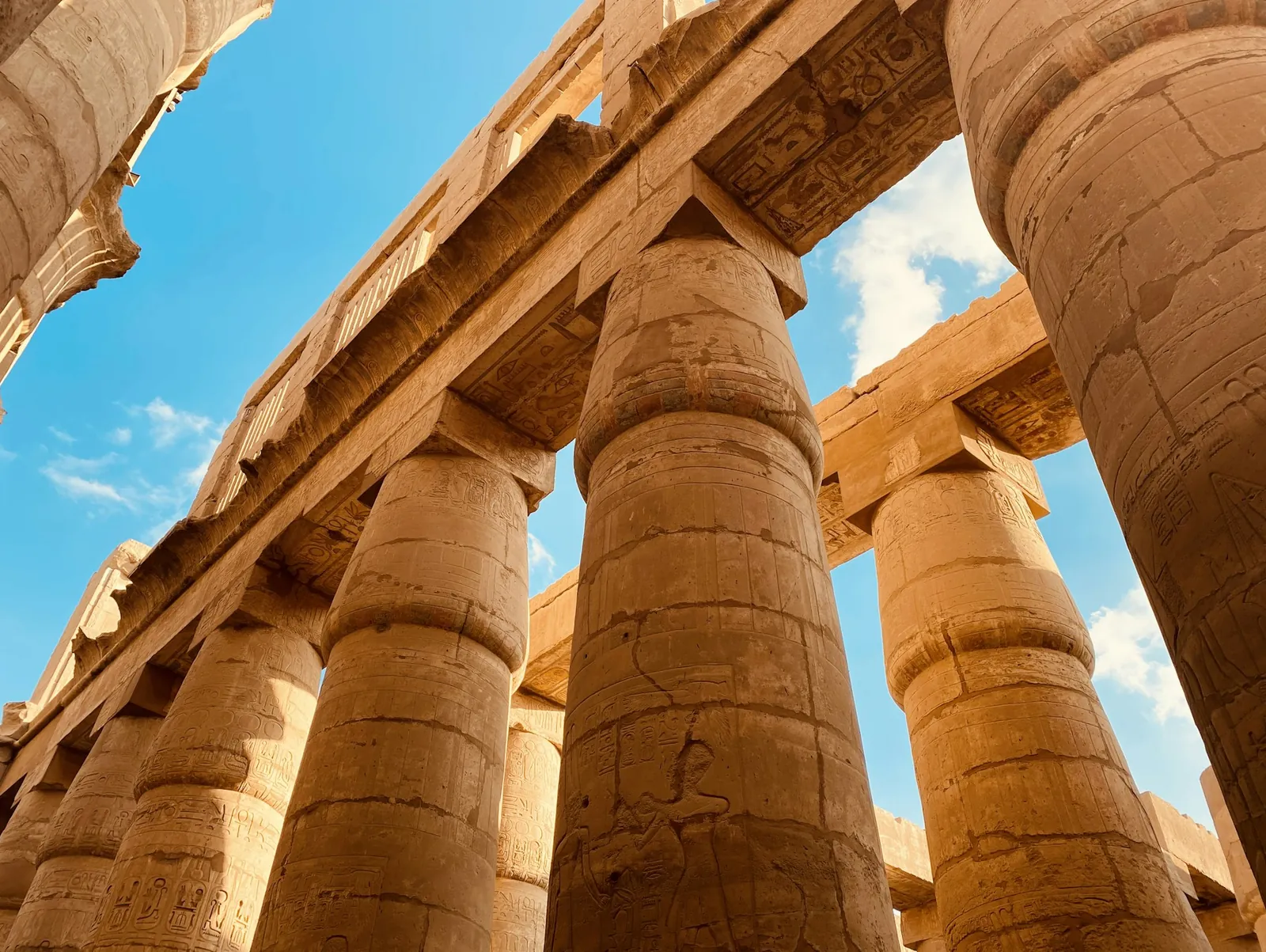 The great sandstone columns of the hypostyle hall at Karnak, rising against a blue sky.