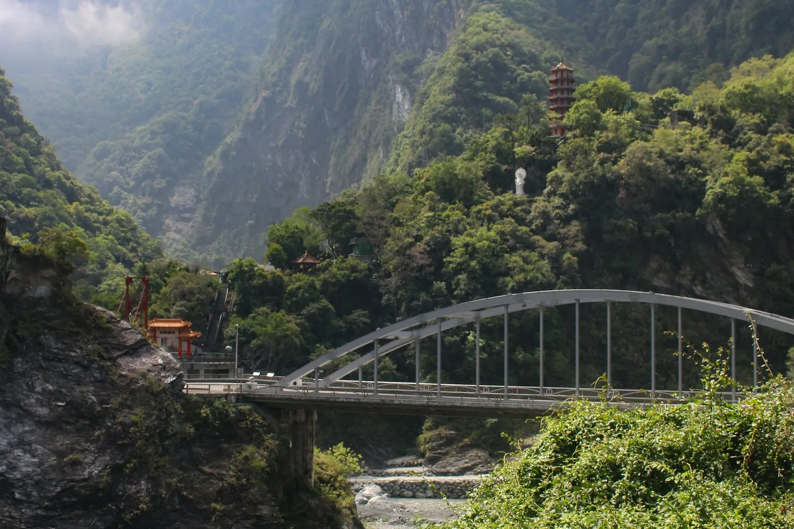 A white arched bridge spanning the forested marble walls of Taroko Gorge.